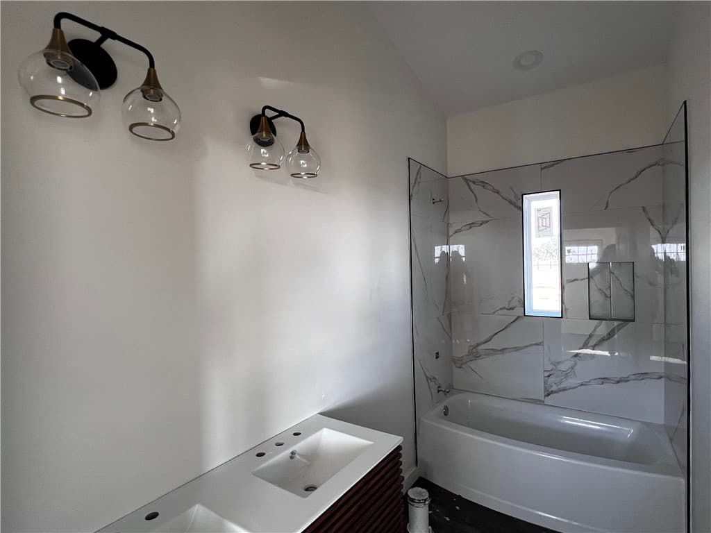 Bathroom with a marble-look tub and shower surround and a double vanity