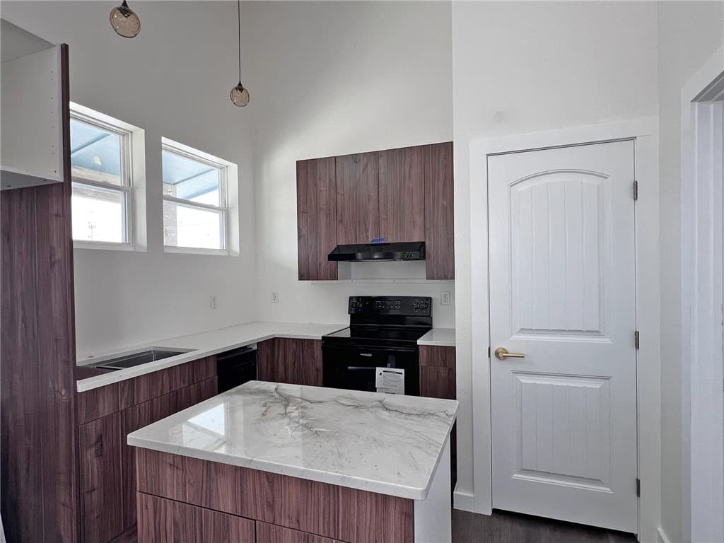 Kitchen with a quartz rolling island, wood cabinets and pendant lights